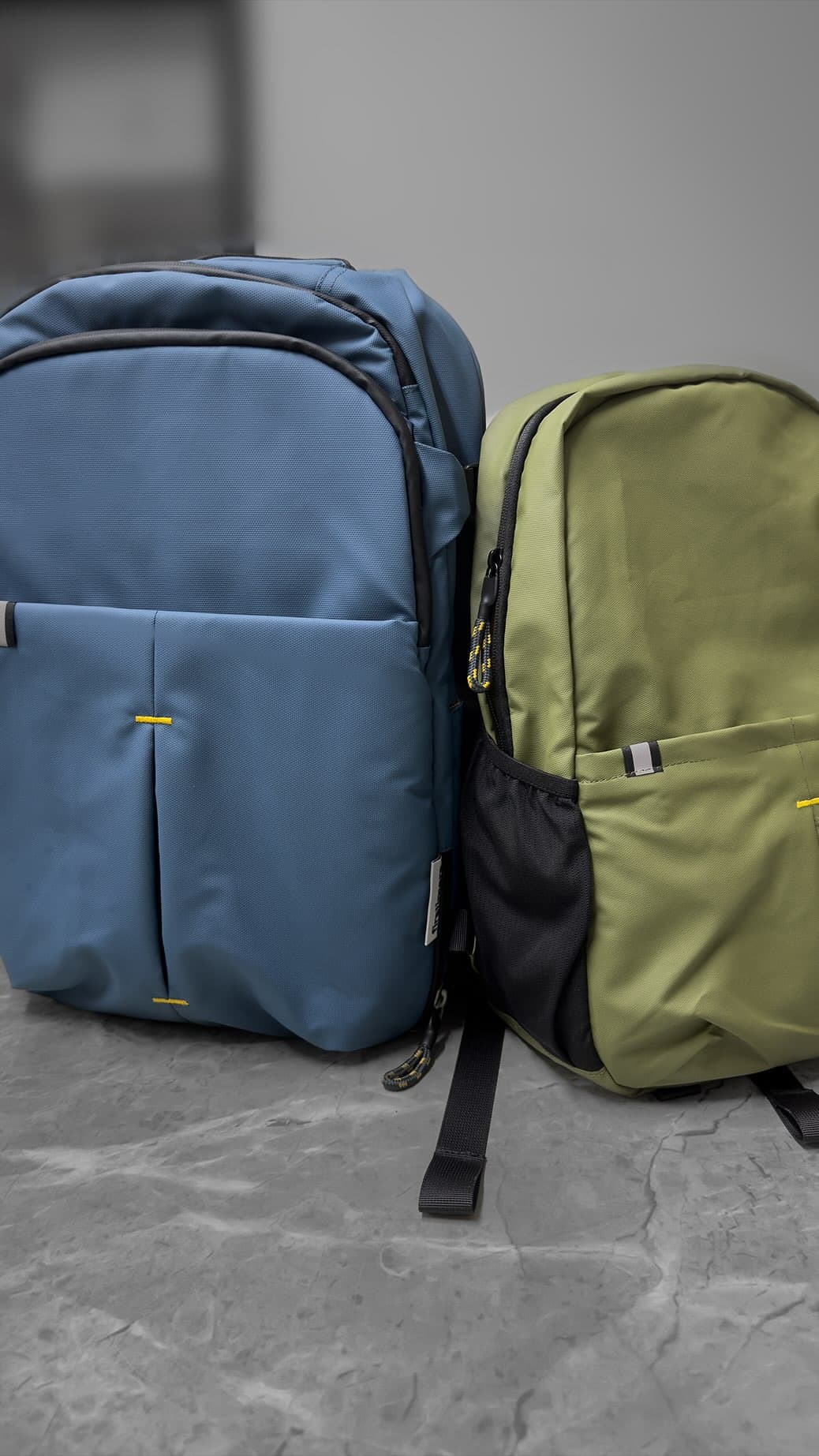 Due zaini personalizzati blu e verde con dettagli gialli, articoli promozionali