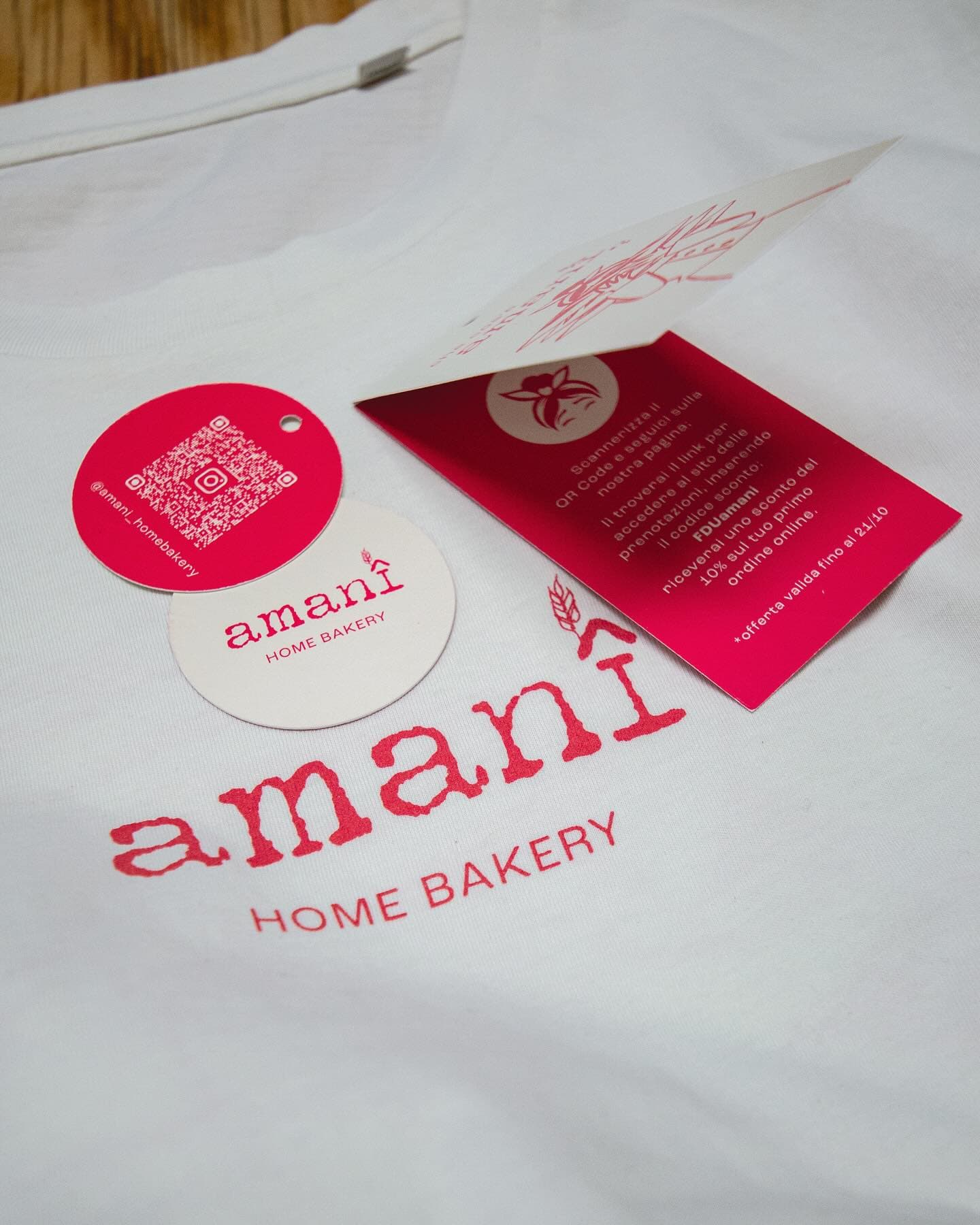 T-shirt bianca personalizzata amanî Home Bakery con cartellini ed etichette QR coordinate, branding completo prodotto con Imago et Inventum